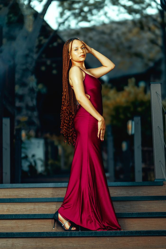 Services Striking portrait of an elegant woman in a red dress posing outdoors on stairs.